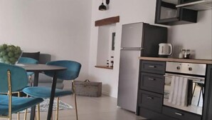 Une cuisine moderne équipée d’un réfrigérateur, d’un four et d’un four à micro-ondes. On y trouve également un coin repas avec des chaises bleues et une table.