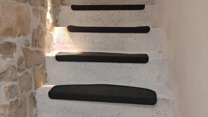 Un mur de pierre sur lequel s’étend une série de marches noires menant à un niveau supérieur.