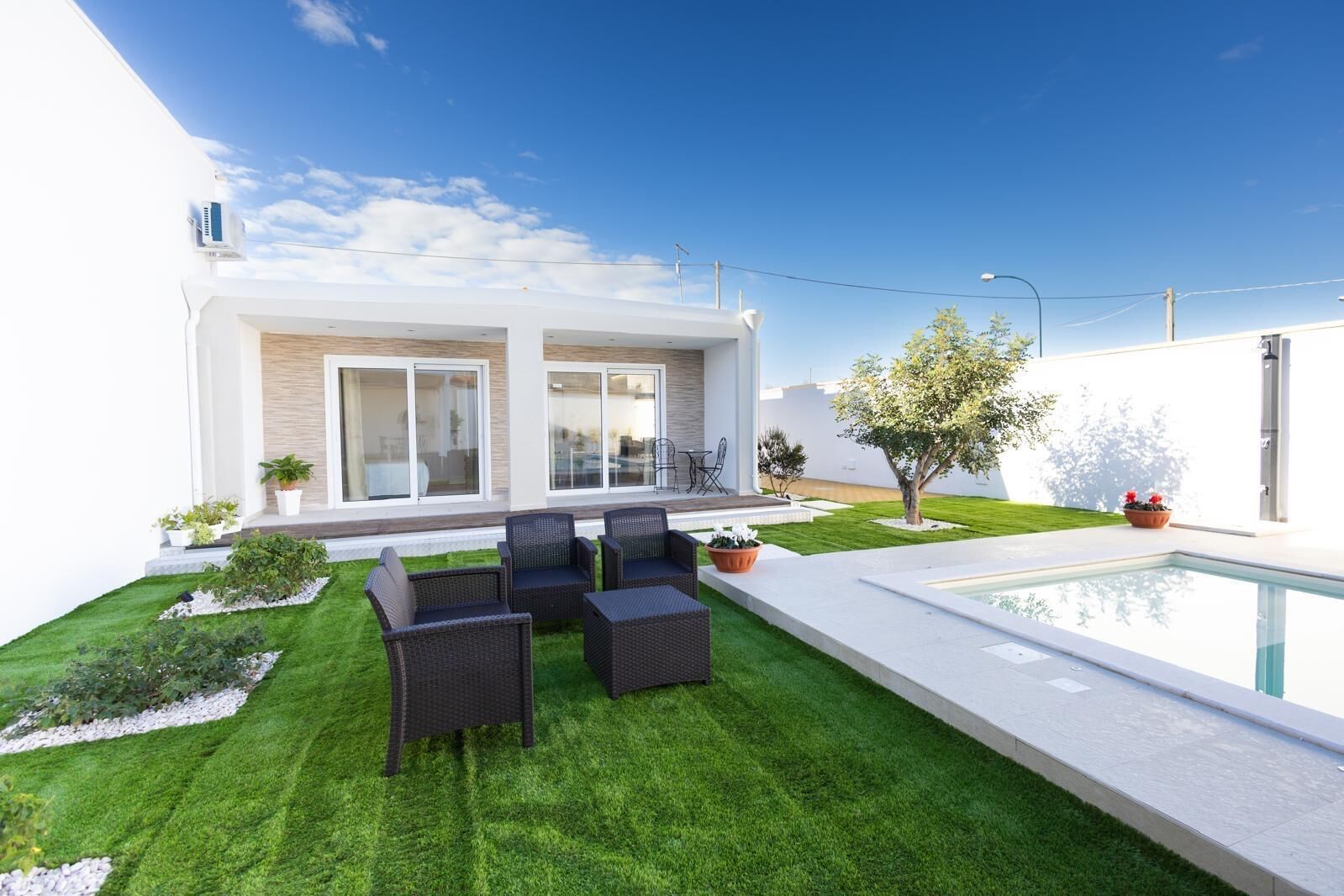 A modern house with a pool, outdoor seating, and a well-maintained lawn.