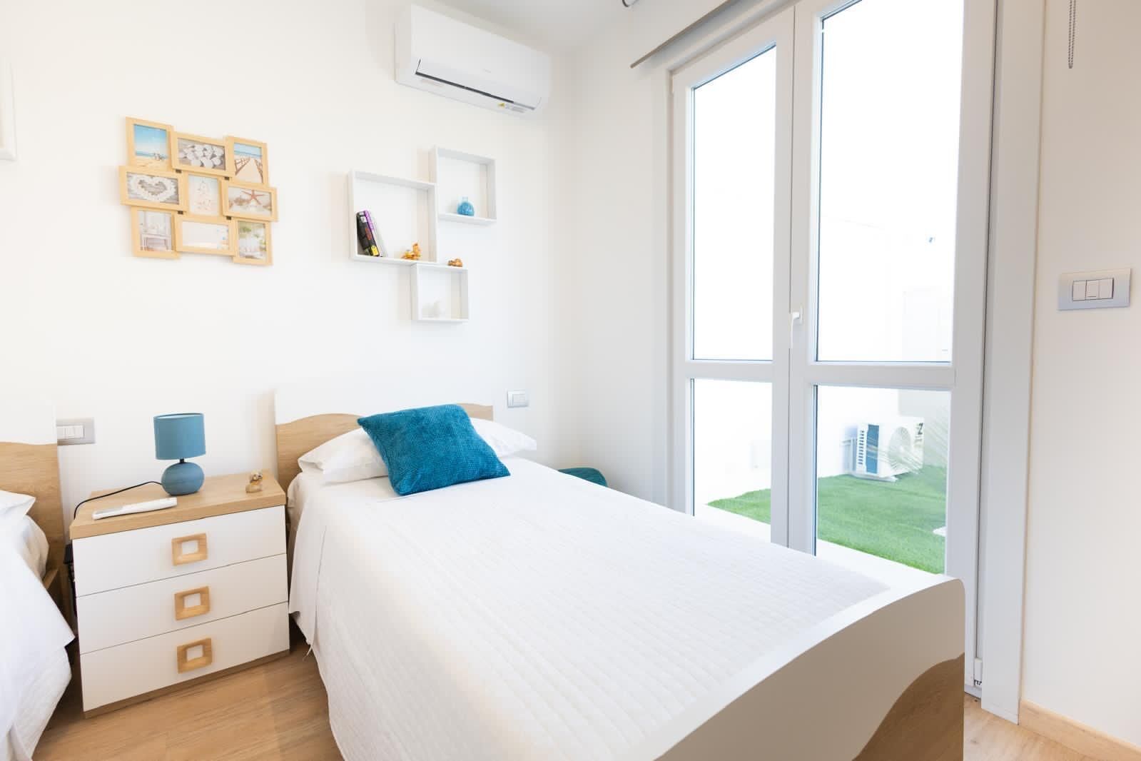 Un dormitorio moderno con una cama grande, una mesita de noche, un aparador y una ventana que ofrece vistas al exterior.
