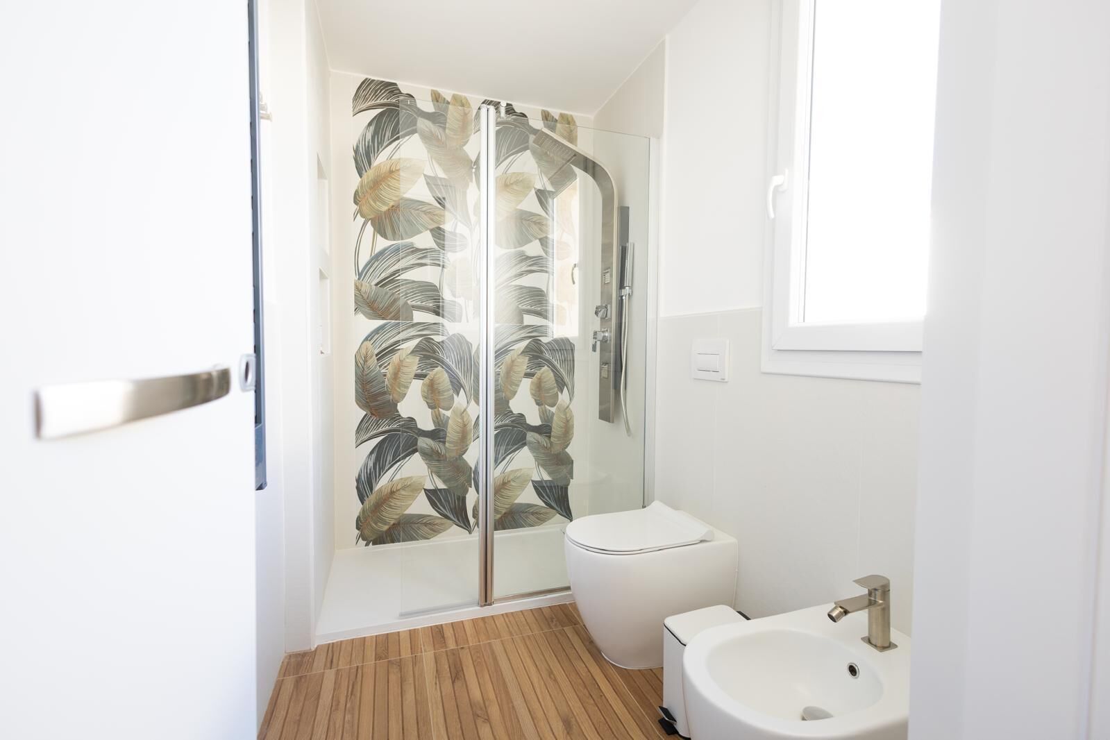 A modern bathroom with a glass shower enclosure, a toilet, and a sink.