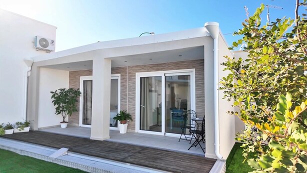 A modern house with a covered patio, sliding glass doors, and a small outdoor seating area.