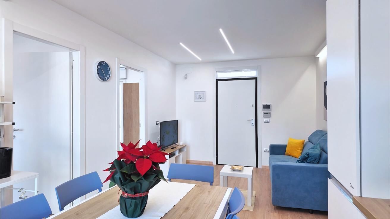 A modern living room with a dining area, a TV, and a door with a lock.
