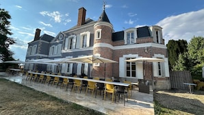 Un edificio grande e histórico con un patio central que incluye mesas al aire libre y un porche cubierto.