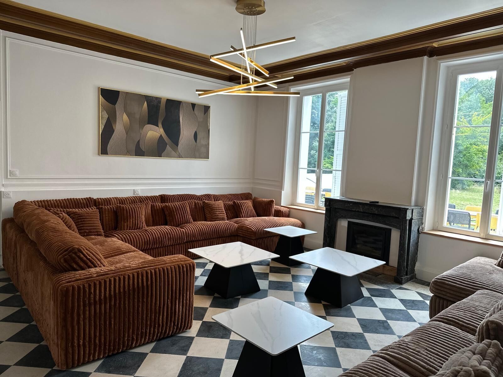 A living room with a large brown sectional sofa, a fireplace, and a checkered floor.