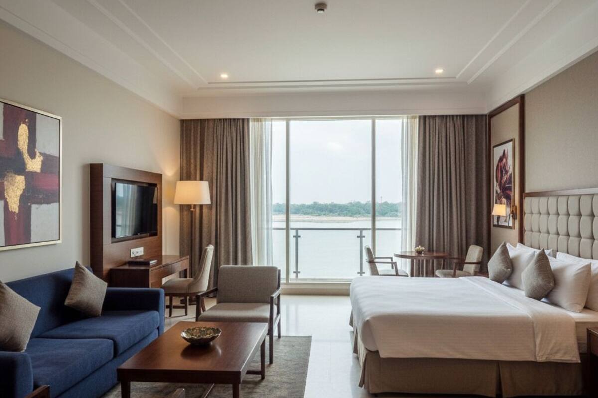 Habitación de hotel con una cama grande, un sofá, un televisor, un escritorio y vista a un cuerpo de agua.