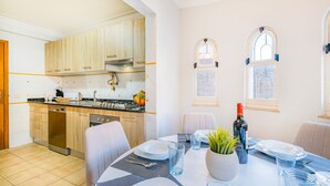 Een moderne keuken met houten kastjes, een gasfornuis en een eethoek met een tafel voor twee personen.
