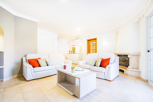 A spacious living room with two white sofas, a coffee table, and a fireplace. - Sophisticated villa with BBQ and heatable pool (Armação de Pêra)