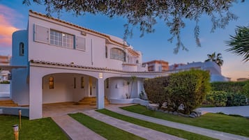 Ein zweistöckiges Haus mit einer überdachten Veranda und einem gepflegten Rasen.