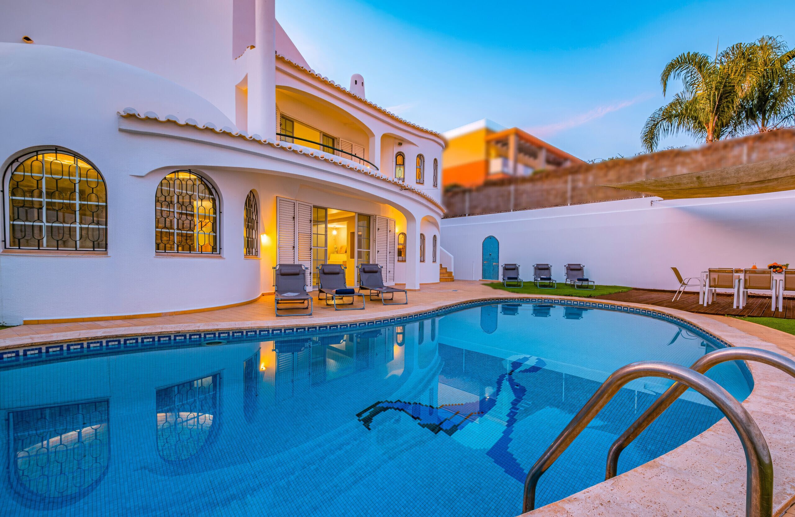 A swimming pool with lounge chairs and a building with arched windows.
