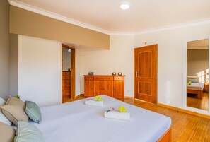Un dormitorio con cama, armario de madera, puerta y espejo.