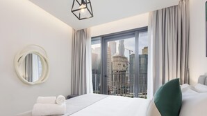A modern hotel room with a large bed, a round mirror, and a view of the cityscape through floor-to-ceiling windows. - LUX The Business Bay Executive Suite (Dubai)