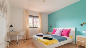 A bedroom with a bed, a desk, a chair, and a window with curtains. - Casa  Emma (isla de Fuerteventura)