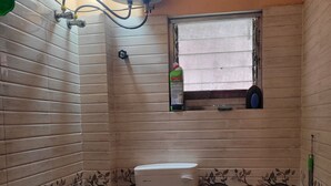 Une petite salle de bain avec des toilettes, une douche et une fenêtre.