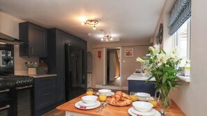 Een moderne keuken met donkere kastjes, een fornuis en een eethoek met een houten tafel gedekt voor het ontbijt.