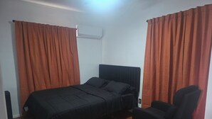 Ein Schlafzimmer mit einem Bett, einem Sessel und einer Klimaanlage.