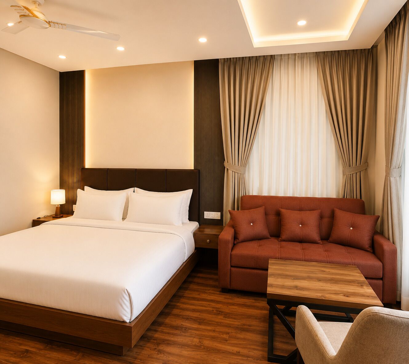 A hotel room with a large bed, a sofa, a wooden coffee table, and a ceiling fan.
