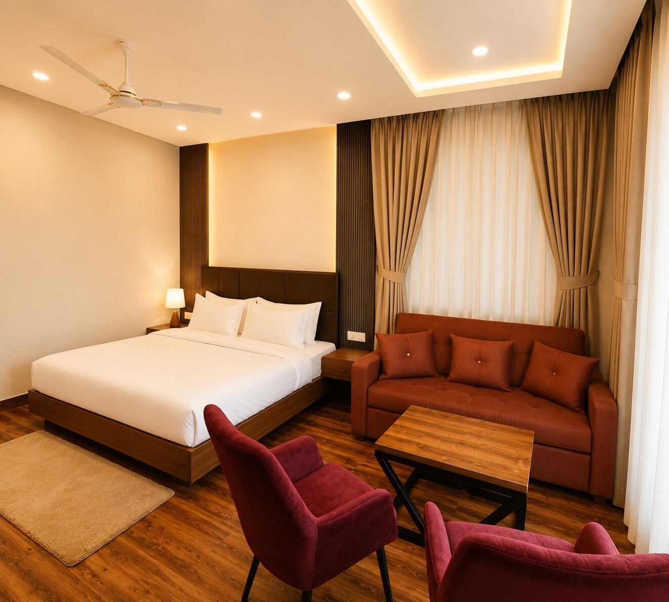 A hotel room with a bed, a sofa, two armchairs, a wooden coffee table, a ceiling fan, and curtains.