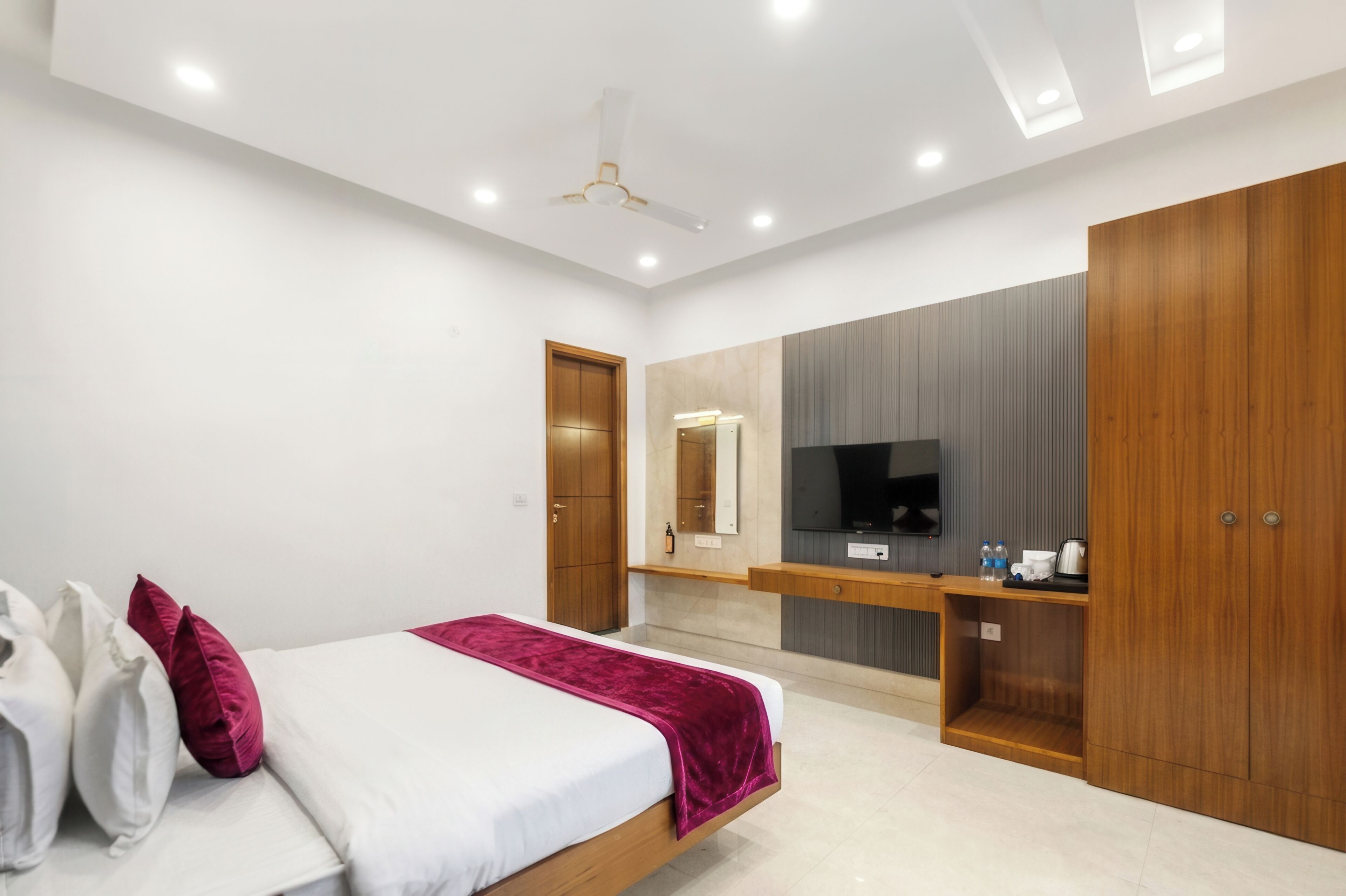 Une chambre moderne comprenant un lit, une armoire en bois, une télévision et une coiffeuse avec un miroir.