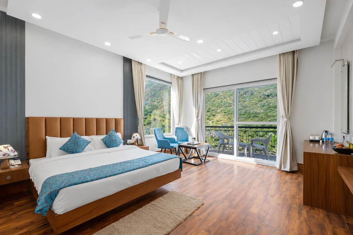 Una habitación de hotel moderna con una cama grande, un balcón con sillas y un escritorio con artículos de cortesía.