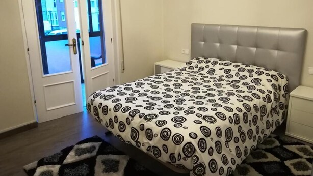 Une chambre à coucher comprenant un lit, une table de chevet, un lustre et une porte à panneaux de verre.