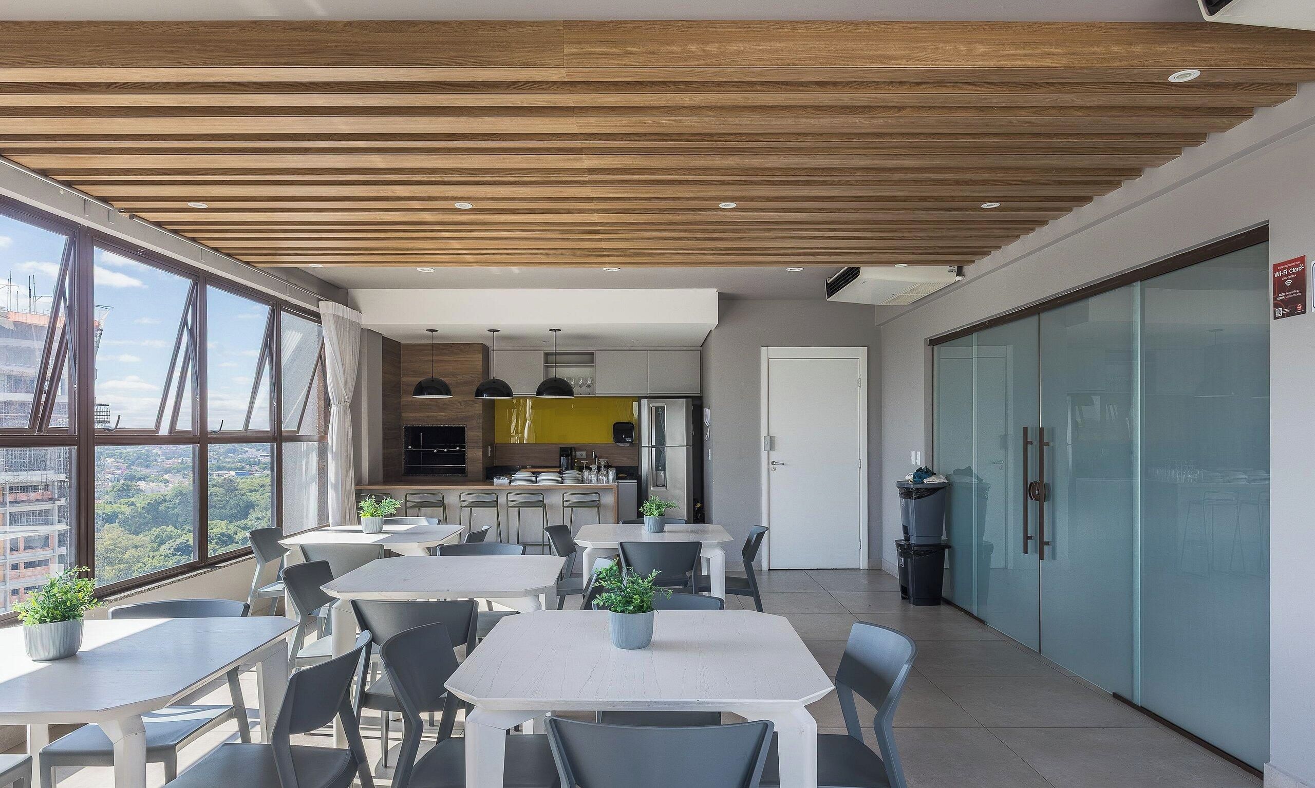 A modern office space with a dining area, kitchen, and large windows offering a view.
