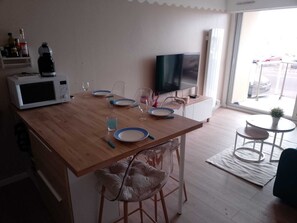 A kitchen with a microwave, dining table, chairs, and a TV. - APARTMENT SEA VIEW FORT MAHON BEACH 50 M FROM THE BEACH (Fort-Mahon-Plage)