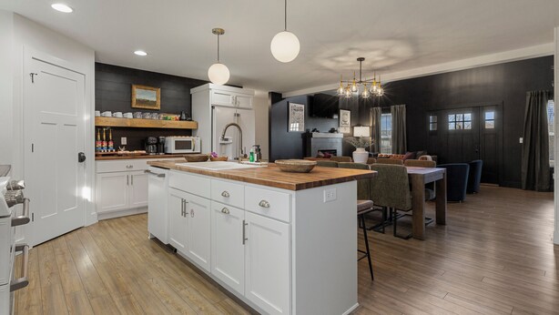 Una cocina moderna con armarios blancos, una isla de madera y un comedor con mesa y sillas.