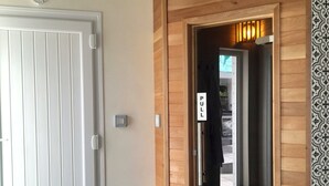 Entrada de hotel con una puerta blanca, un tirador, un interruptor de luz y un letrero que dice 'TIRAR'.