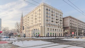 A multi-story building with balconies, a street in the foreground, and a snow-covered ground. - Lumina airy apartment with balcony (Warsaw)