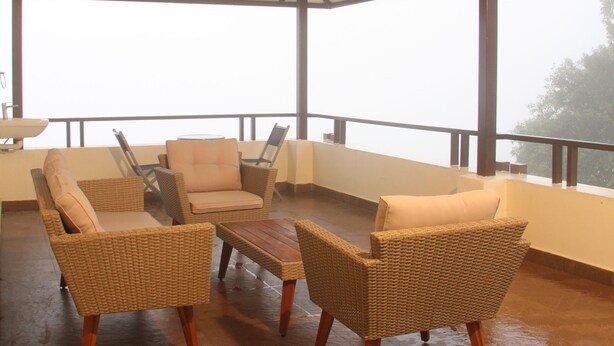 Un área de estar al aire libre techada, con mobiliario de mimbre y piso de madera.