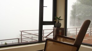Una habitación con una mecedora, ventanas amplias y una pequeña mesa con una planta.