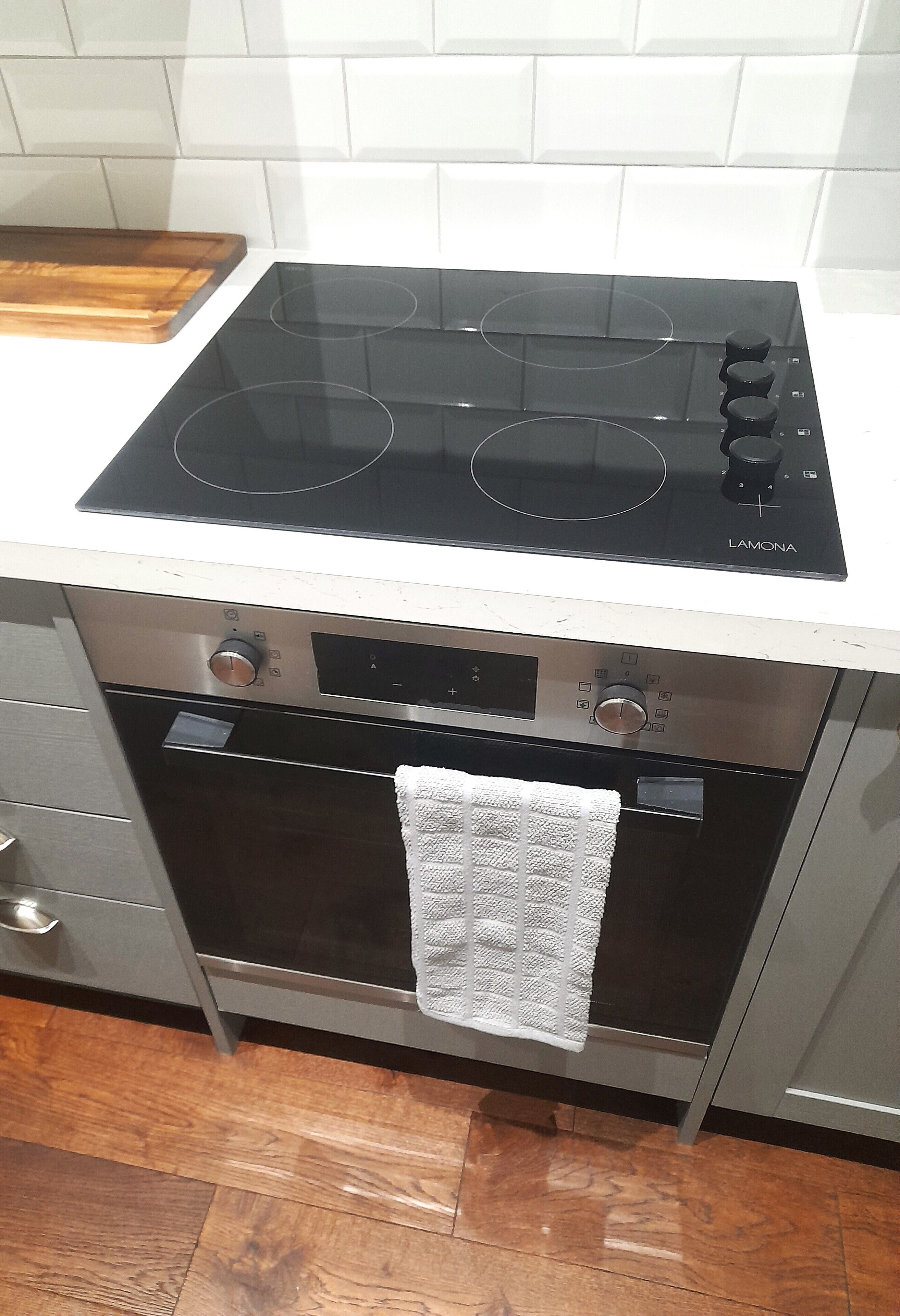 A kitchen with a black stove top, oven, and a wooden cutting board on the countertop.