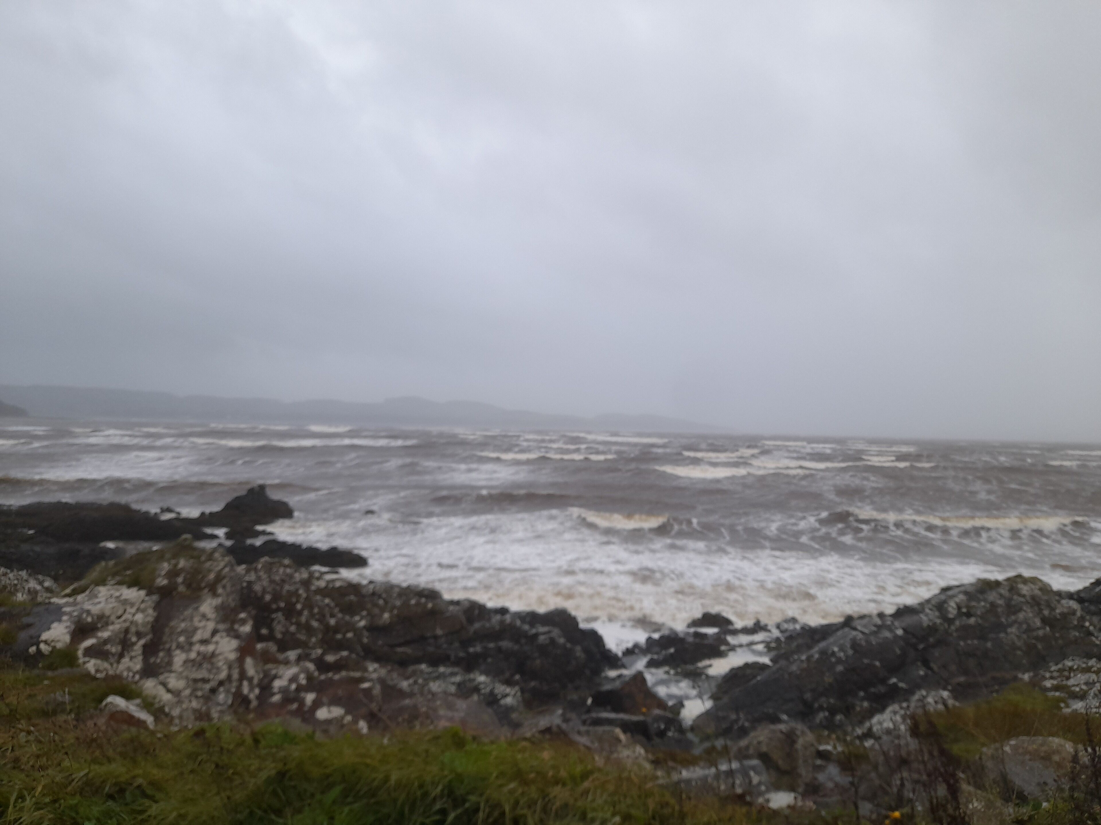 Un paysage côtier avec une mer agitée et un terrain rocheux.