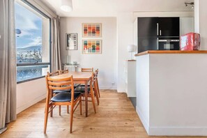 A compact kitchen with a dining area, a large window, and a view of the outdoors. - Elegant Apartment Paris 16th - Near the Seine (Paris)