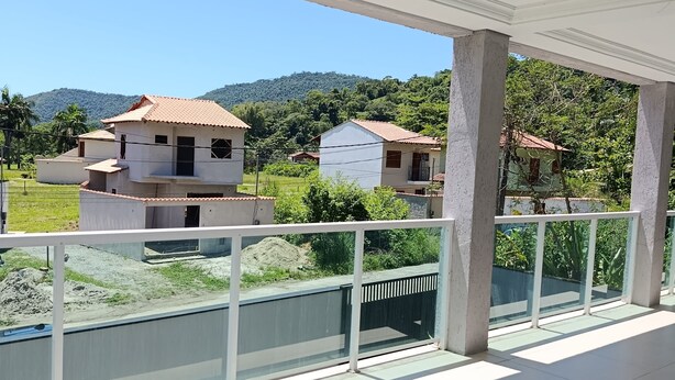 Ein überdachter Balkon mit Blick auf Häuser und eine hügelige Landschaft.