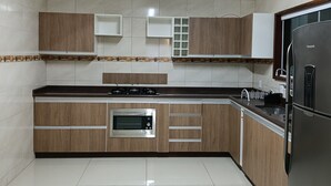 Eine moderne Küche mit Holzschränken, einem eingebauten Ofen und einem Edelstahlkühlschrank.