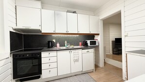 A compact kitchen with white cabinets, a black tiled backsplash, a microwave, a coffee maker, and a dishwasher.