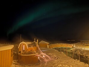 A wooden cabin with a hot tub and a covered area, surrounded by snow and a wooden fence. - Central and cozy 1-bedroom apartment in the heart of Tromsø (Troms)
