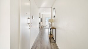 A hallway with a wooden floor, white walls, a door with a handle, a small table with a lamp, and a mirror on the wall. - F rum Terrace by Minhos Guest (Braga)