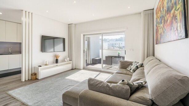 A modern living room with a sofa, TV, and a sliding glass door leading to a balcony. - F rum Terrace by Minhos Guest (Braga)