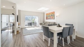A modern living room with a dining area, a sofa, a coffee table, and a painting on the wall. - F rum Terrace by Minhos Guest (Braga)