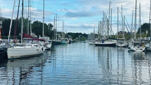 A marina with multiple sailboats docked along a calm waterway, surrounded by buildings and greenery. - Family home 2 steps from the port and downtown. Sleeps 8. (Vannes)