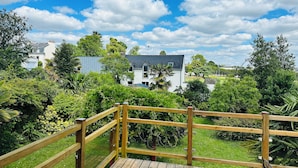 A wooden deck with a view of a white house and surrounding greenery. - Family home 2 steps from the port and downtown. Sleeps 8. (Vannes)