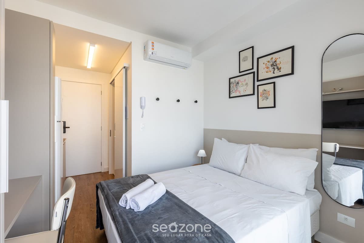 Habitació d'hotel amb llit, una taula de nit, un mirall i un telèfon fixat a la paret.