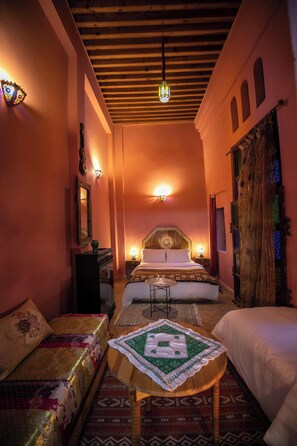 A cozy room with a bed, a sofa, and a small table, featuring a wooden ceiling and warm lighting. - Spacious 5-bedroom riad in lovely Fès with AC and fitness room (Fès)