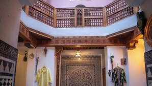 A dining area with a high ceiling, a patterned wall, and a large ornate door. - Spacious 5-bedroom riad in lovely Fès with AC and fitness room (Fès)