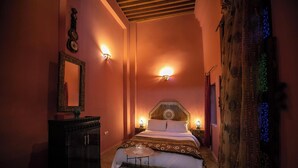A cozy bedroom with a large bed, a nightstand, a dresser, and a mirror. - Spacious 5-bedroom riad in lovely Fès with AC and fitness room (Fès)
