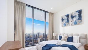 A modern hotel room with a large bed, a city view, and two abstract paintings on the wall. - LUX  The Phantom Sky Pool Suite (Dubai)