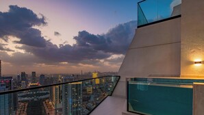 A high-rise building with a glass balcony overlooking a cityscape at dusk. - LUX  The Phantom Sky Pool Suite (Dubai)
